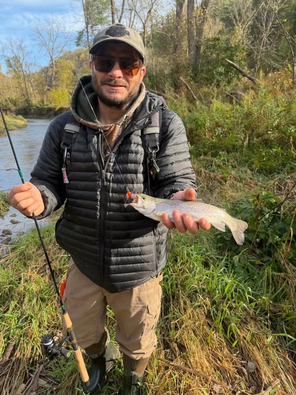 Angler on a trout stream holding a trout caught on a Gapen Spin-Bee with a T-Grub